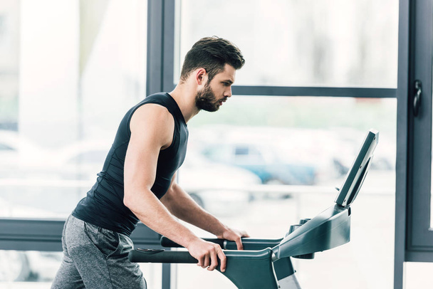 handsome sportsman running on treadmill at sports center - Photo, Image