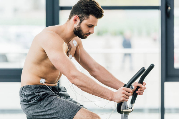muscular sportsman with electrodes training on elliptical during endurance test in gym - Zdjęcie, obraz