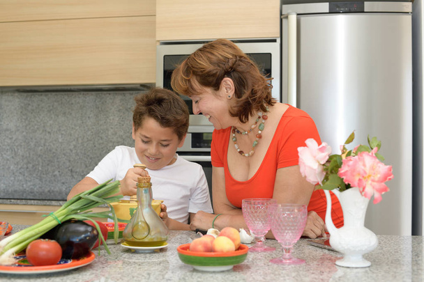 Ευτυχισμένη μητέρα και γιος προετοιμάζοντας το γεύμα με ένα κονίαμα - Φωτογραφία, εικόνα