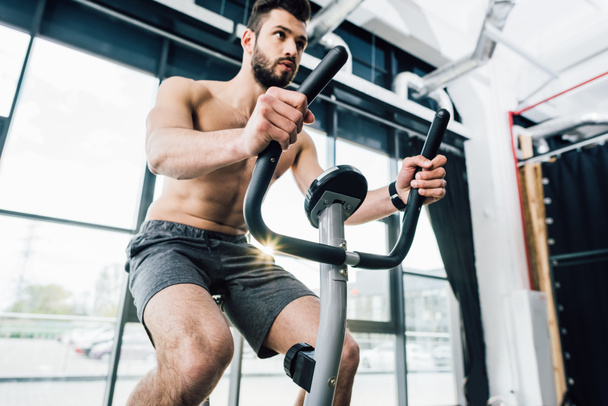 handsome bearded sportsman training on elliptical machine at gym - Фото, изображение