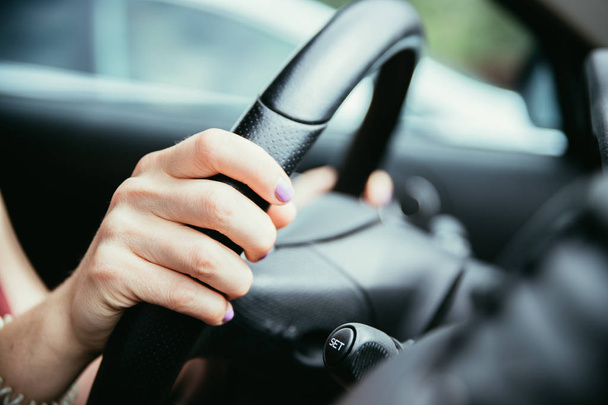 Sports car steering wheel, hands of a young girl with purple nai - Φωτογραφία, εικόνα