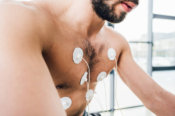 Ausgeschnittene Ansicht eines Sportlers mit Elektroden beim Krafttraining im Fitnessstudio - Foto, Bild