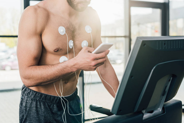 nyírt kilátás sportolók az okostelefon futó futópad alatt állóképességi vizsgálat edzőteremben - Fotó, kép