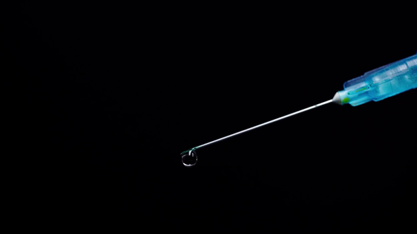 blue syringe with drop on water falling from needle isolated on black  - Footage, Video