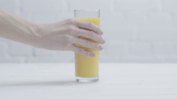 vista cortada da mulher colocando vidro de suco de laranja fresco na mesa
  - Filmagem, Vídeo