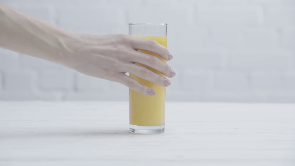 cropped view of woman taking glass of fresh orange juice  - Filmati, video