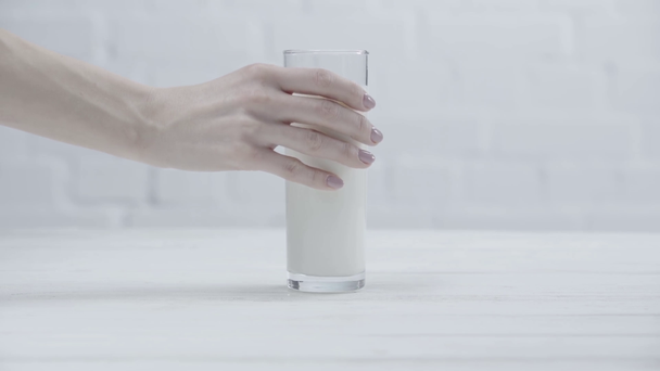 przycięte widok kobiety oddanie szklanki świeżego mleka na stole  - Materiał filmowy, wideo