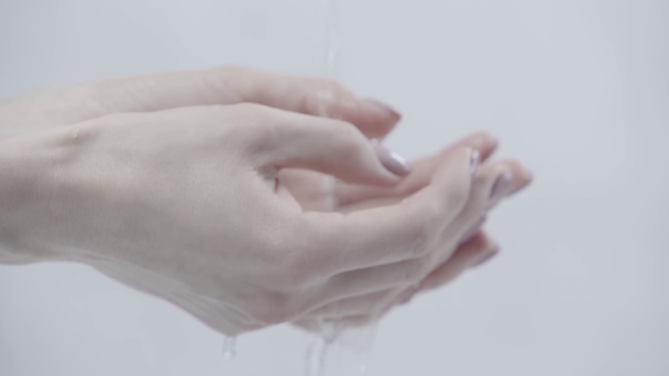 przycięte widok kobiety z cupped ręce w pobliżu nalewania wody na szarym  - Materiał filmowy, wideo