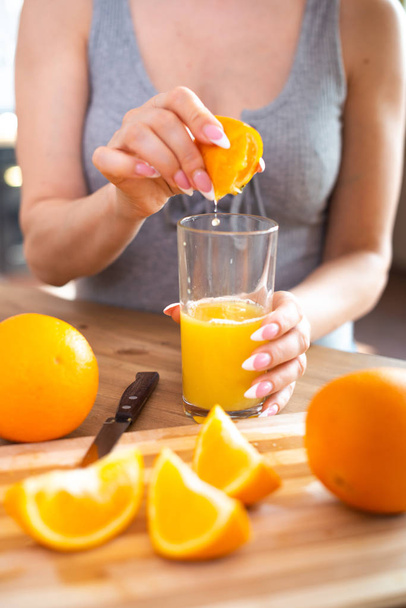 cooking, food and concept of veganism, vigor and healthy eating - close up of female hand squeeze fresh orange juice - Foto, afbeelding