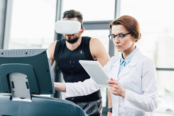 desportista em realidade virtual fone de ouvido correndo em esteira perto médico durante teste de resistência
  - Foto, Imagem