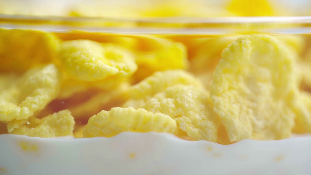 selective focus of crispy and tasty cornflakes in glass bowl filling with milk - Footage, Video