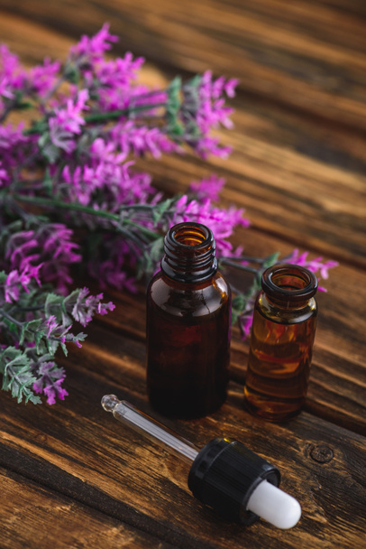 heather plant, bottles with essential oils and dropper on wooden surface - Photo, Image