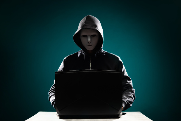 Retrato de hacker en máscara blanca y sudadera con capucha. Cara oscura y oscura. Ladrón de datos, fraude en internet, dark net y ciberseguridad
. - Foto, Imagen