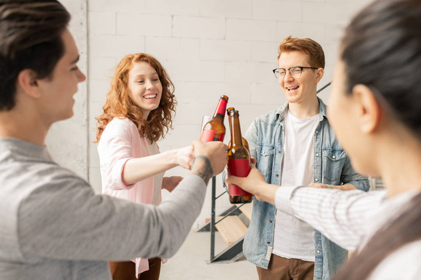 Група молодих веселих друзів у повсякденному одязі, що стоять по колу і клінкінг з напоями на домашній вечірці
 - Фото, зображення