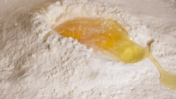 ακατέργαστο αυγό κοτόπουλου βρίσκεται σε αλεύρι λευκού σίτου, προετοιμασία για ζύμωμα ζύμη, αργή κίνηση - Πλάνα, βίντεο