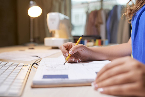 Close-up de designer feminino sentado no local de trabalho e desenho com lápis no caderno ou fazer anotações sobre planos futuros
 - Foto, Imagem