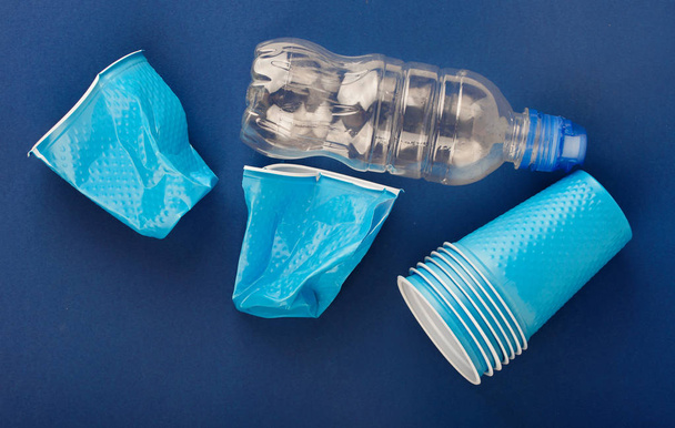 青い背景にプラスチックカップ - 写真・画像