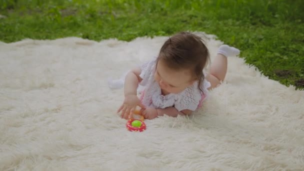 Una chica muy pequeña y hermosa jugando en la colcha en el parque
. - Metraje, vídeo