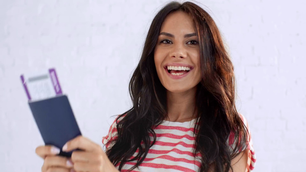 šťastná mladá žena s úsměvem na kameře, ukazující prstem na pas a letenku, skákání a ukazování vítězného gesta - Záběry, video