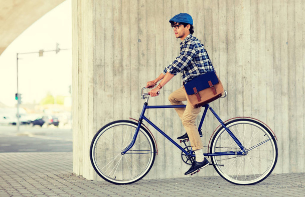 young hipster man with bag riding fixed gear bike - 写真・画像