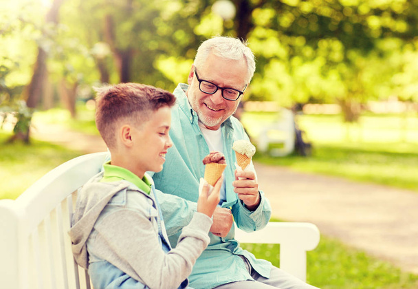 hombre viejo y niño comiendo helado en el parque de verano
 - Foto, Imagen