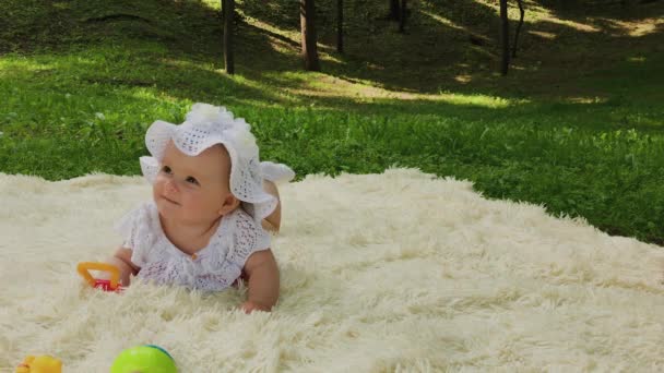 Una chica muy pequeña y hermosa jugando en la colcha en el parque
. - Metraje, vídeo
