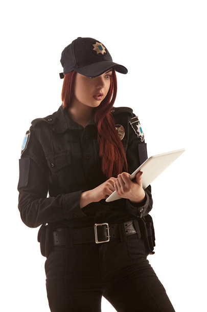 赤毛の女性警官は、白い背景に隔離されたカメラのためにポーズをとっています. - 写真・画像