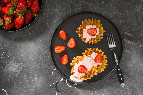 Waffles with strawberries on a black plate on a dark background - Foto, Imagem