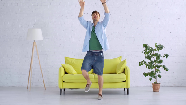time lapse of cheerful young man dancing in spacious living room at home - Materiaali, video