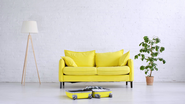 upływ czasu całkiem młoda kobieta pakowania letnich ubrań w żółtej torby na kółkach na podłodze w domu - Materiał filmowy, wideo