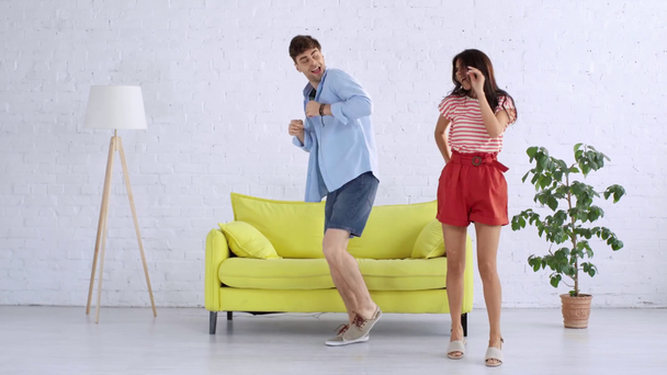 tijd verval van vrolijke, jonge man en vrouw dansen in ruime woonkamer thuis - Video