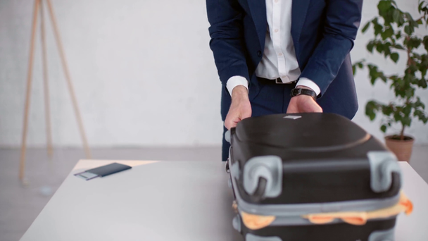 cropped view of businessman in formal wear packing summer clothes, flippers and swimming mask in suitcase at home - Footage, Video