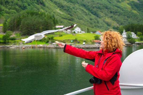 Woman traveling on ferry boat and feeding seagull - Photo, Image