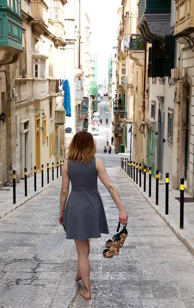 Valletta, Malta-5 may,2019:Young woman caucasian white walking in old street in Valletta, capital of Malta, girl in the city, walking. Typical street of Valletta, Malta. Tourist in the city - Fotó, kép