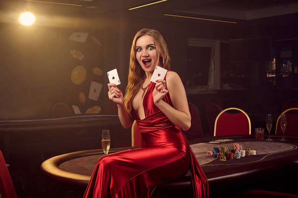 Młoda piękna kobieta pozuje przeciwko stołowi pokerowemu w luksusowym kasynie. - Zdjęcie, obraz