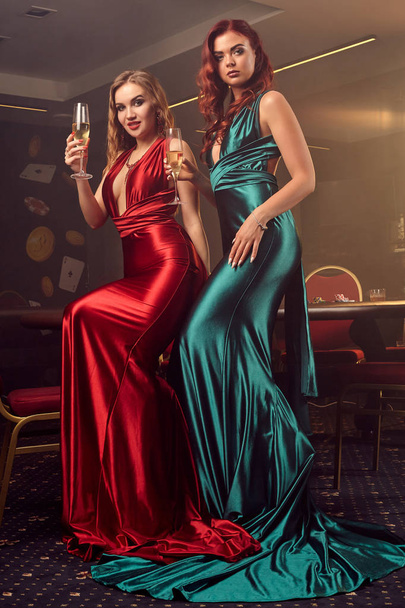 İki güzel kadın lüks kumarhanede poker masasına karşı poz veriyor.. - Fotoğraf, Görsel