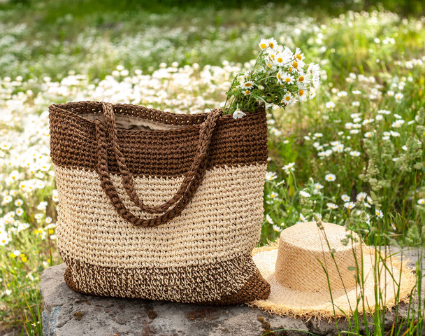Summer beige-brown knitted bag and yellow straw hat on the stone - Photo, Image