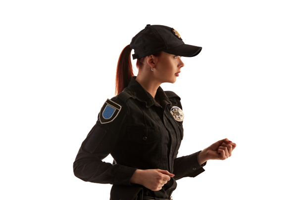 Close-up shot of a redheaded female police officer posing for the camera isolated on white background. - Photo, image