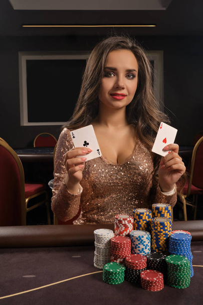 Красива брюнетка грає в покер, сидячи за столом в казино
. - Фото, зображення