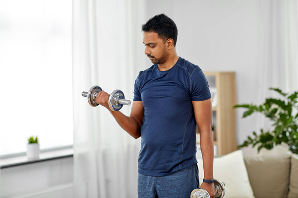 indian man exercising with dumbbells at home - Foto, Bild