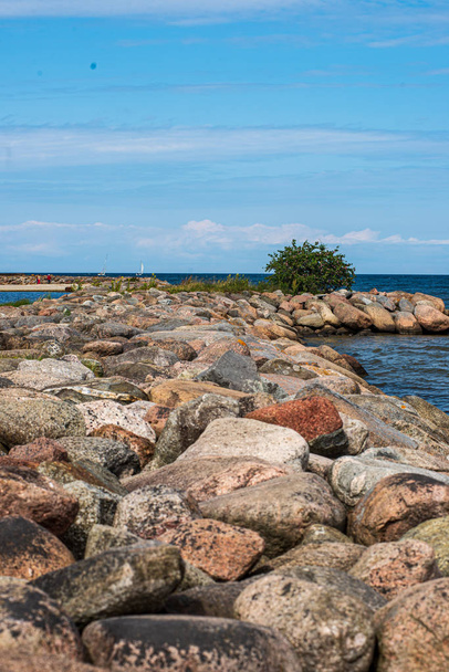 praia de mar vazia solitária com areia branca, pedras grandes e madeira velha
 - Foto, Imagem
