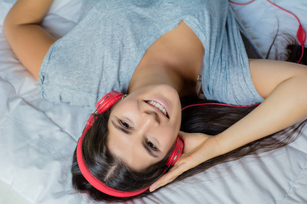 Young woman enjoying music on bed. - Photo, image