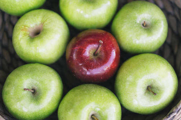 Vista de cerca de unas manzanas verdes coloridas saludables y una manzana roja en una canasta y los sabrosos beneficios de cada una. Sé diferente.
 - Foto, imagen