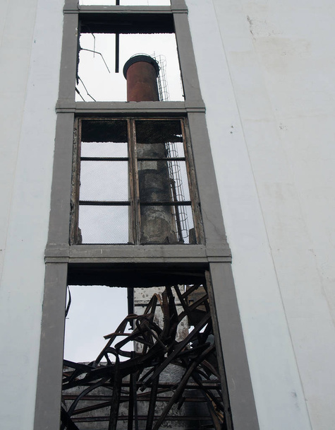 widok przez okno opuszczonego budynku fabryki z wysokim komina widoczne wewnątrz ruin - Zdjęcie, obraz