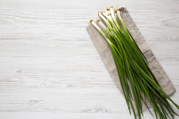 Fresh green onions on a white wooden background, top view. From  - Valokuva, kuva