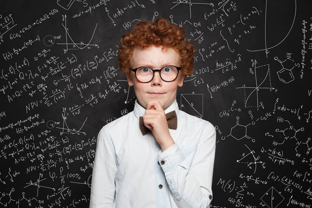 Pensant enfant garçon étudiant sur fond tableau noir avec des formules scientifiques
 - Photo, image
