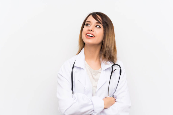junge Ärztin mit isoliertem Hintergrund blickt lächelnd auf - Foto, Bild