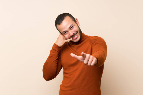 Kolumbiai férfi garbó pulóvert, hogy telefonon gesztus és mutatott elöl - Fotó, kép