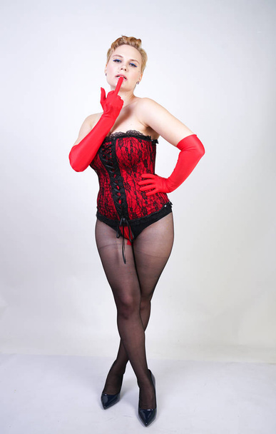 sexy plus taille femme aux cheveux courts dans un corsage en dentelle rouge et collants noirs classiques transparents avec une couture posant sur un fond blanc dans le Studio
 - Photo, image