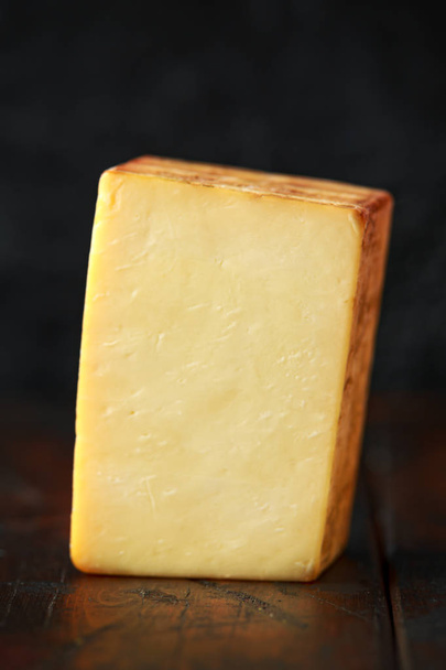 Bitesize Rebanada de queso cheddar ahumado sobre fondo rústico de madera
 - Foto, imagen